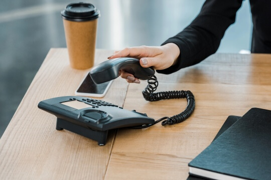 Frau greift zum Telefonhörer Frau greift zum Telefonhörer